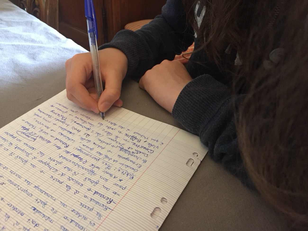 Adolescent écrivant sur une copie