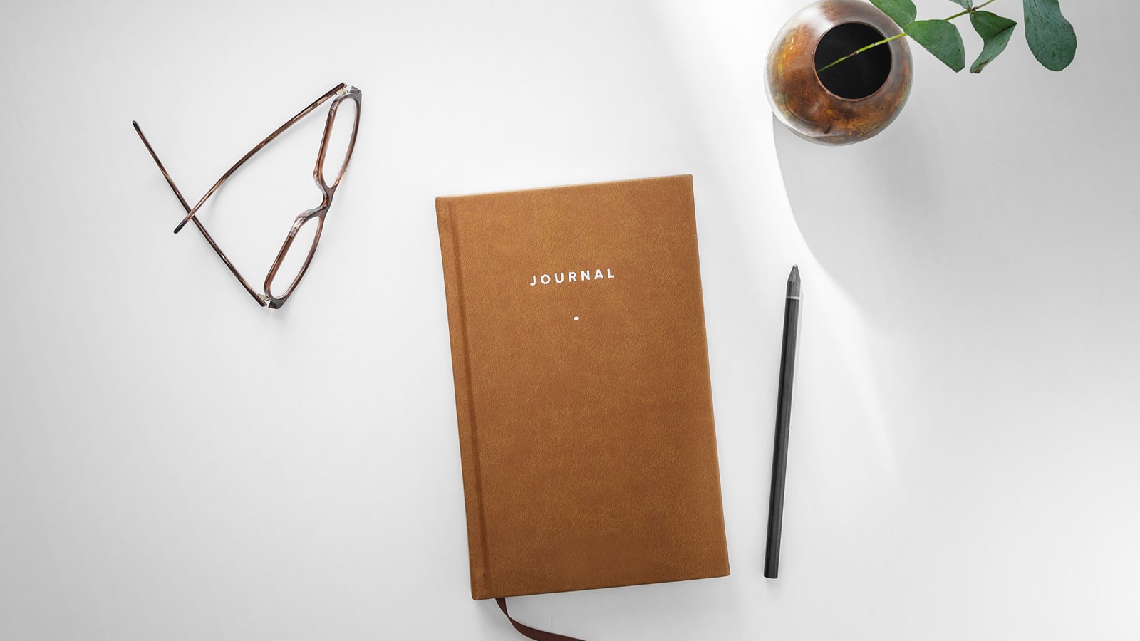 Carnet, lunettes et crayon sur une table blanche